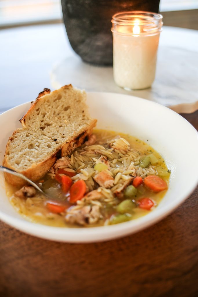 lemon chicken orzo soup served in a white bowl with crusty bread