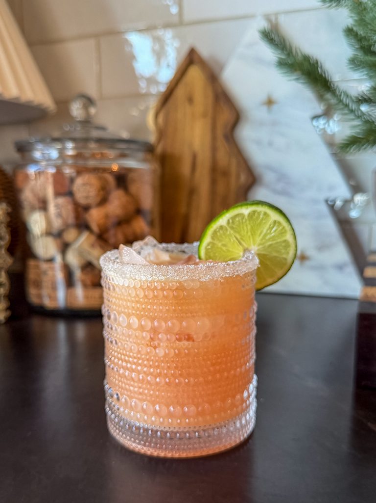 coconut blood orange margarita in a glass garnished with sugar and a lime wheel