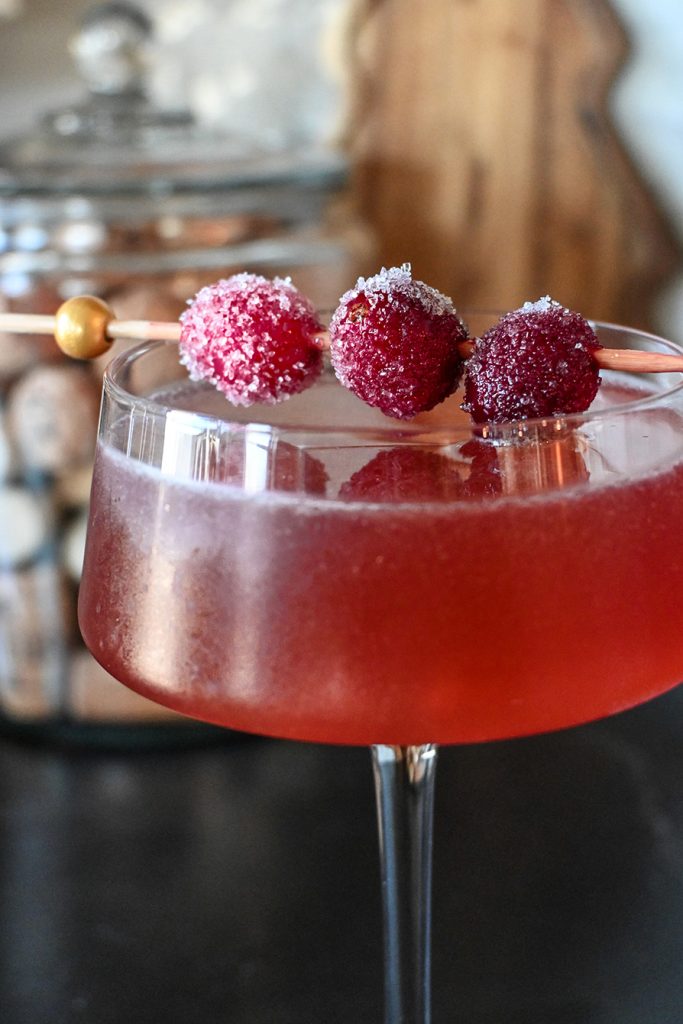 Cramberry bourbon martini
a red cocktail in a coupe style glass garnished with sugared cranberries